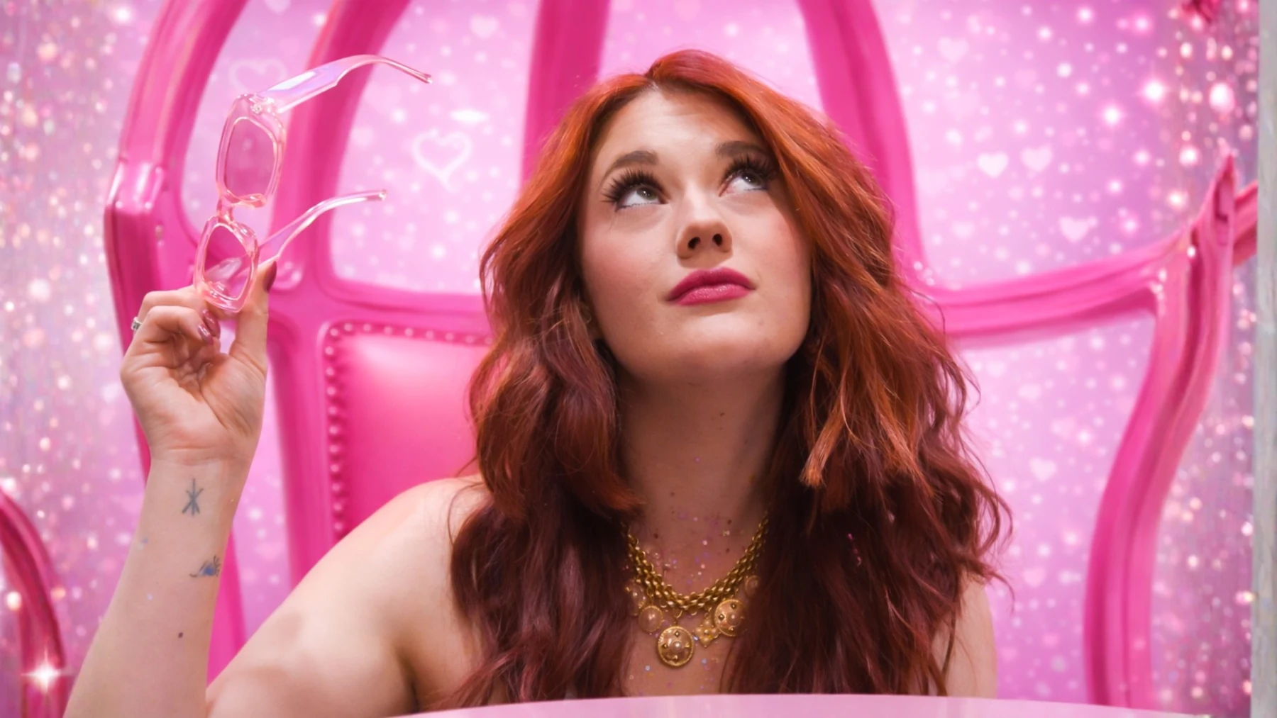Sydney in a pink chair, holding her pink sunglasses